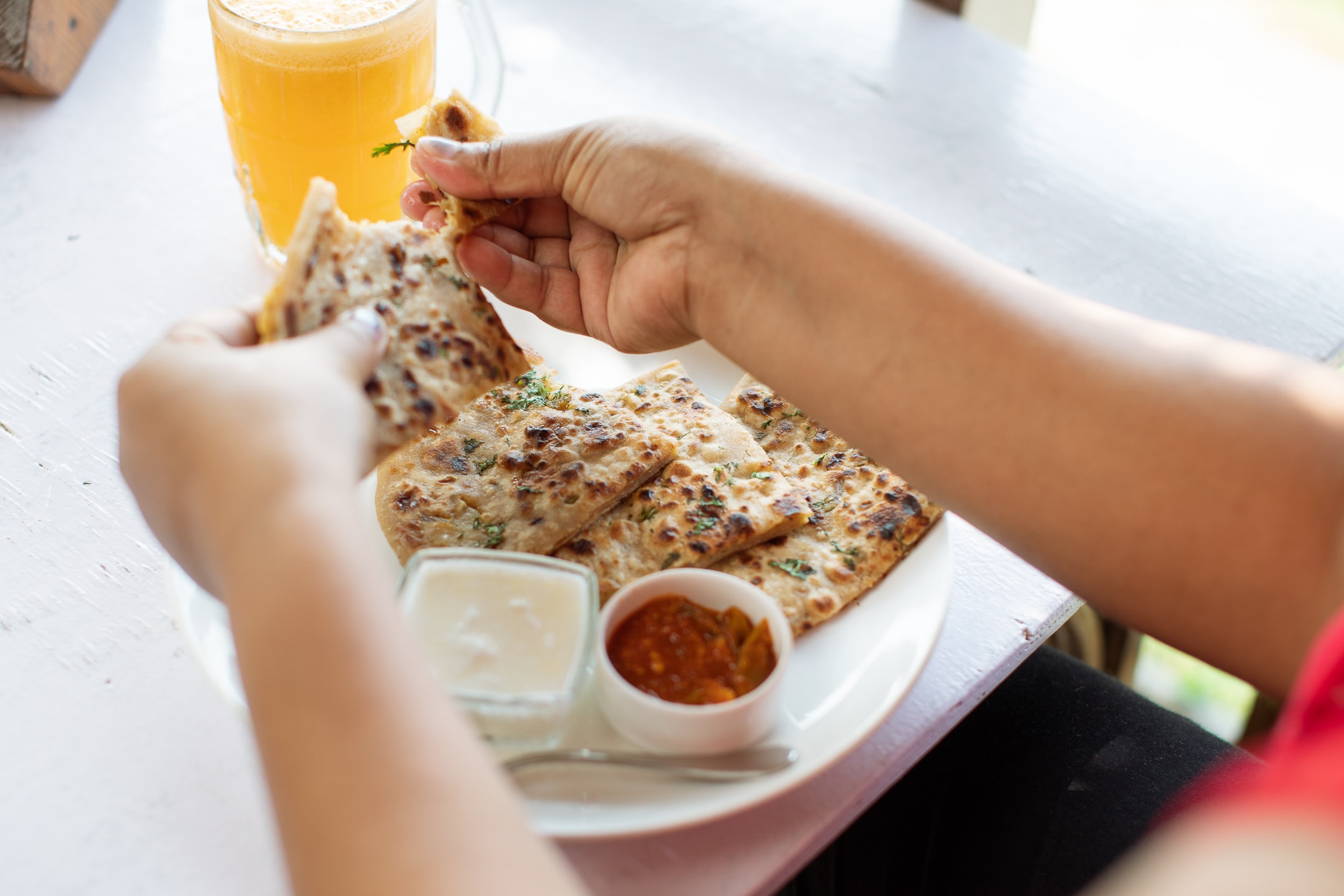 Enjoying Aloo Paratha with the hand, mango pickle, fresh homemade curd and fresh orange juice